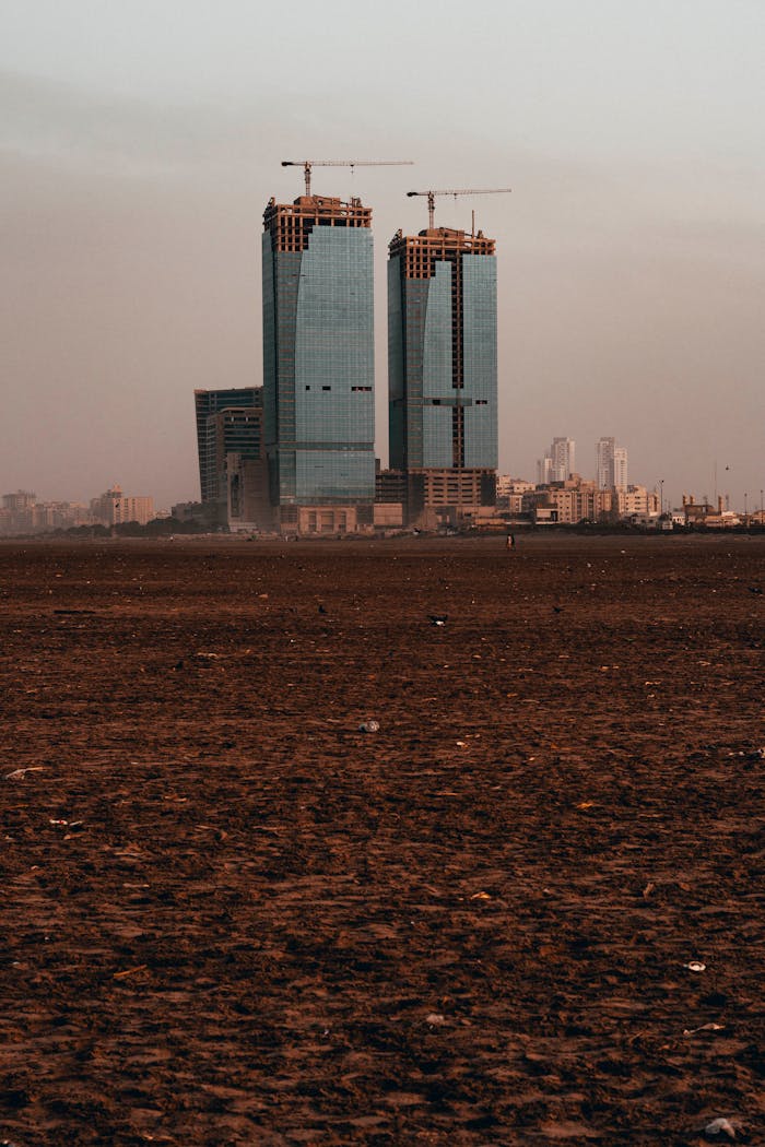 about-02 Skyscrapers under construction in a cityscape during daytime with construction cranes on top.